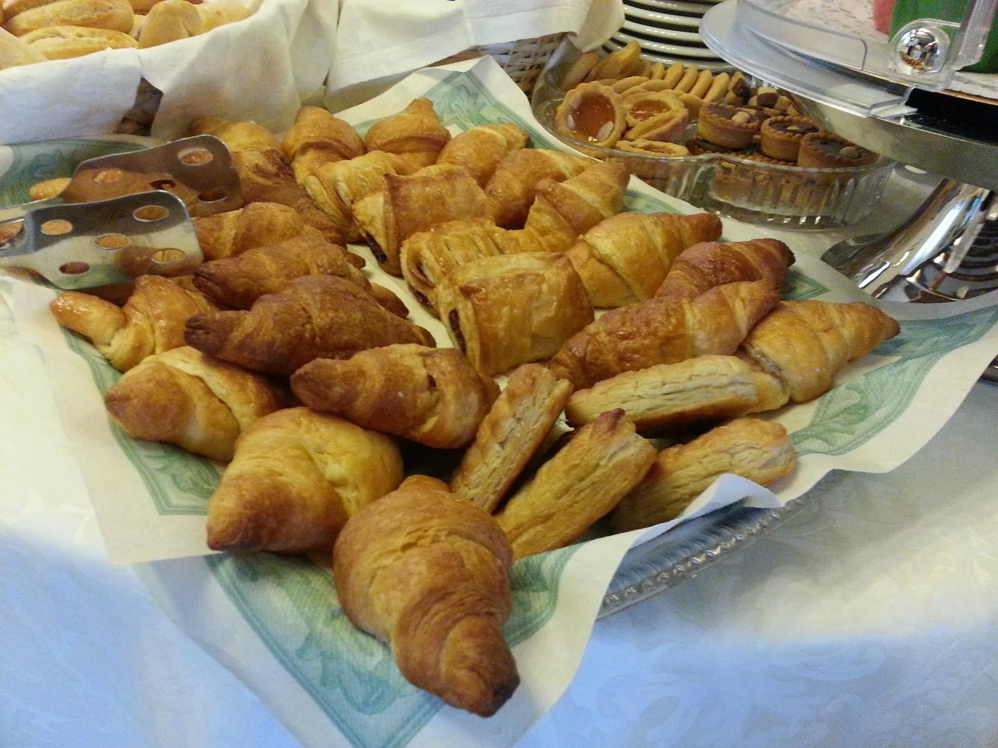 A variety of pastries, including croissants and other baked goods, displayed on a table.