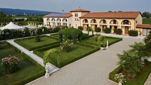 Un grand bâtiment doté d’un jardin à la disposition symétrique, agrémenté de haies taillées, de parterres de fleurs et de statues.