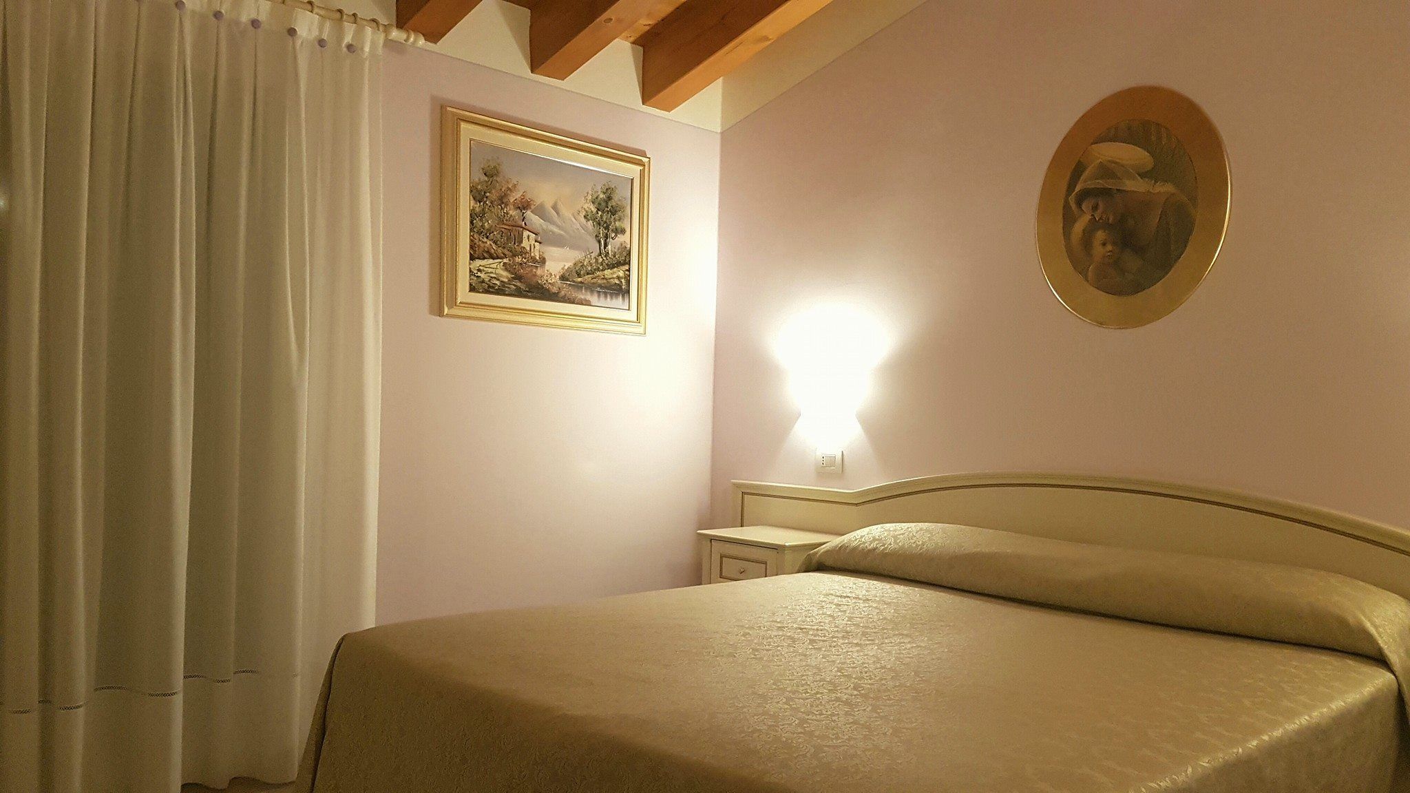 Un dormitorio con cama, mesita de noche, un cuadro y una lámpara de pared.