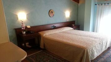 Habitación de hotel con cama, mesitas de noche, lámpara de pared y un pequeño adorno sobre la cama.