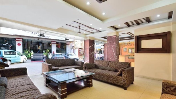 A hotel lobby with patterned sofas, a glass coffee table, and a reception desk. - Gaylord International (NEW DELHI)