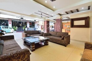 A hotel lobby with patterned sofas, a glass coffee table, and a reception desk. - Gaylord International (NEW DELHI)