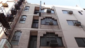 A multi-story building with a brick facade, multiple air conditioning units, and a fire escape on the left side. - Gaylord International (NEW DELHI)