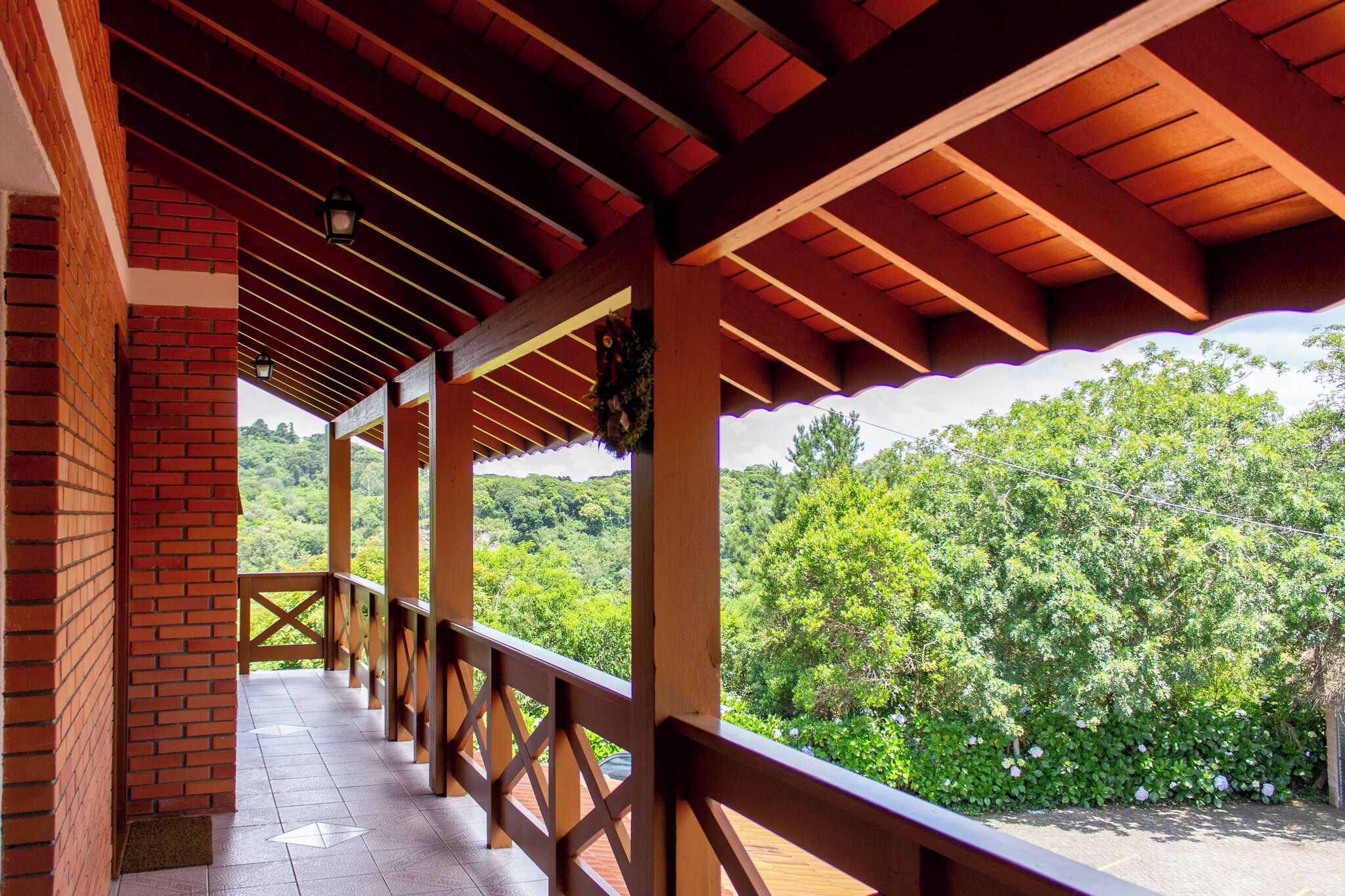 Un espacio al aire libre cubierto con barandilla de madera, paredes de ladrillo y vistas a un paisaje verde exuberante.