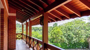 Un espacio al aire libre cubierto con barandilla de madera, paredes de ladrillo y vistas a un paisaje verde exuberante.
