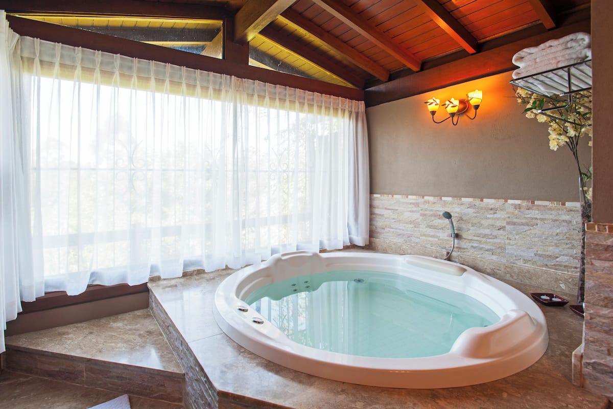 Un área de spa con un jacuzzi, una pared de piedra y una ventana con cortinas translúcidas.