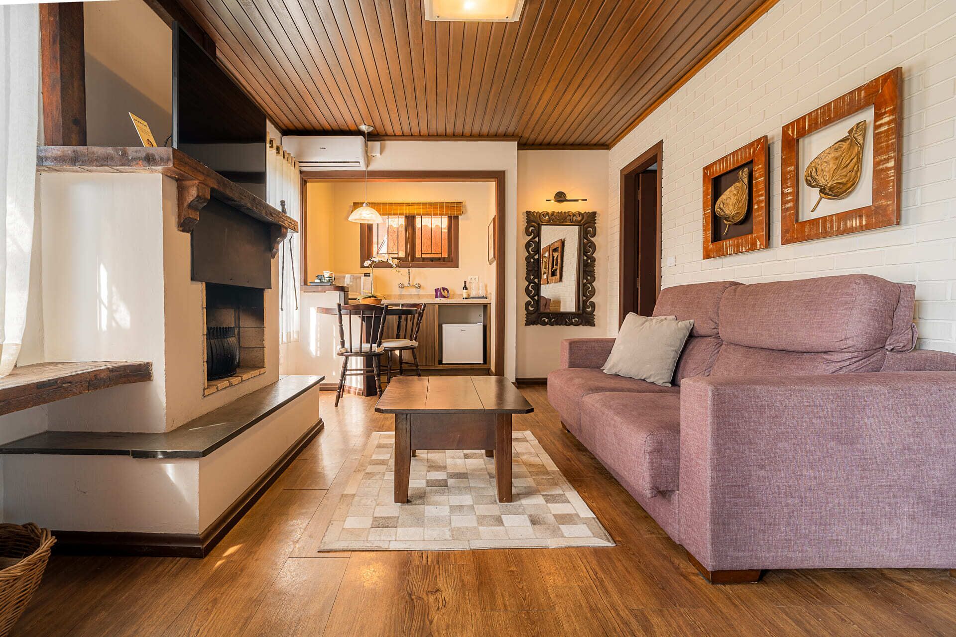 Una sala de estar acogedora con chimenea, un sofá, una mesa de centro y una cocina al fondo.