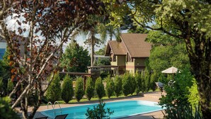 Una casa a due piani con piscina, immersa nel verde curato e con vista sul cielo.