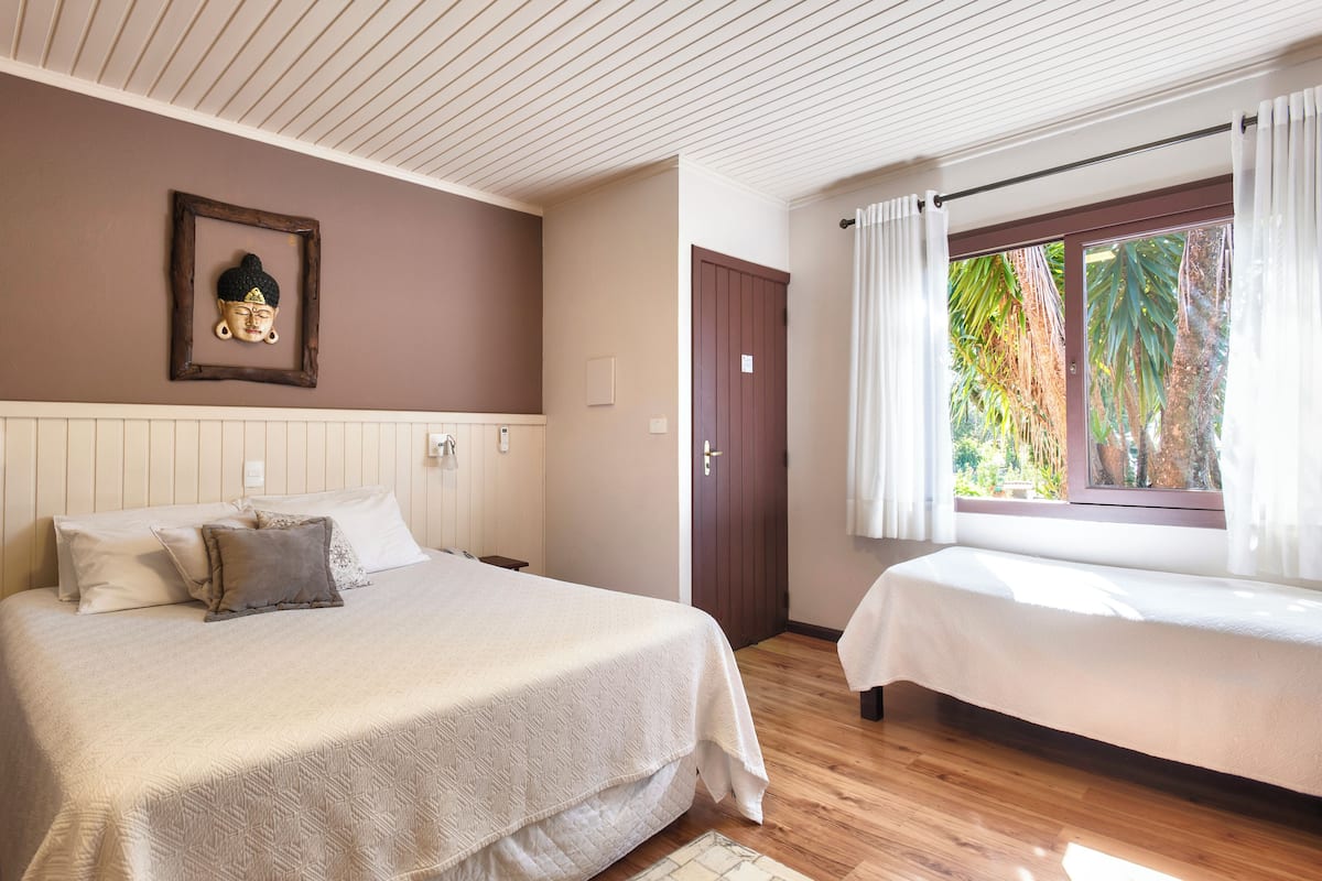 Un dormitorio con cama, mesita de noche y ventana con cortinas.
