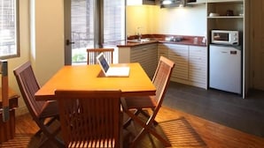 A compact kitchen with a dining area, wooden chairs, a table, and a microwave. - Sejuk Suites (Legian)