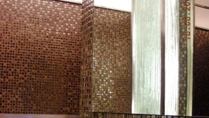 A bathroom with a tiled wall, a mirror, and a bathtub.