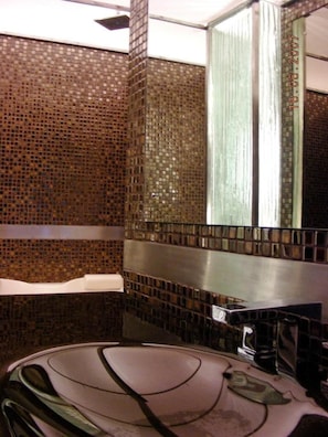 A bathroom with a tiled wall, a mirror, and a bathtub.