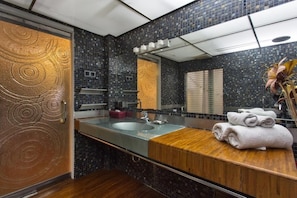 A bathroom with a large mirror, a sink, and a wooden vanity.
