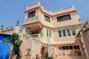 Un edificio de varios pisos con techo plano, balcones y plantas en macetas.