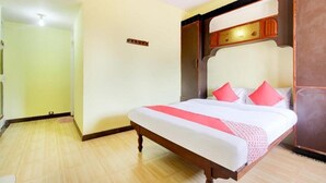 A hotel room with a bed, wooden headboard, and a small wooden cabinet. - Gaffino's Beach Resort (Cavelossim)