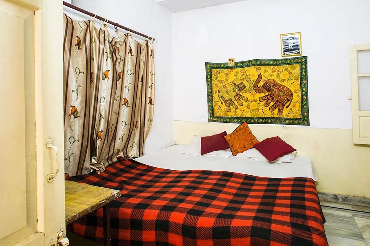 Una habitación con una cama, una colcha a cuadros, cortinas con estampado floral y un cuadro en la pared.