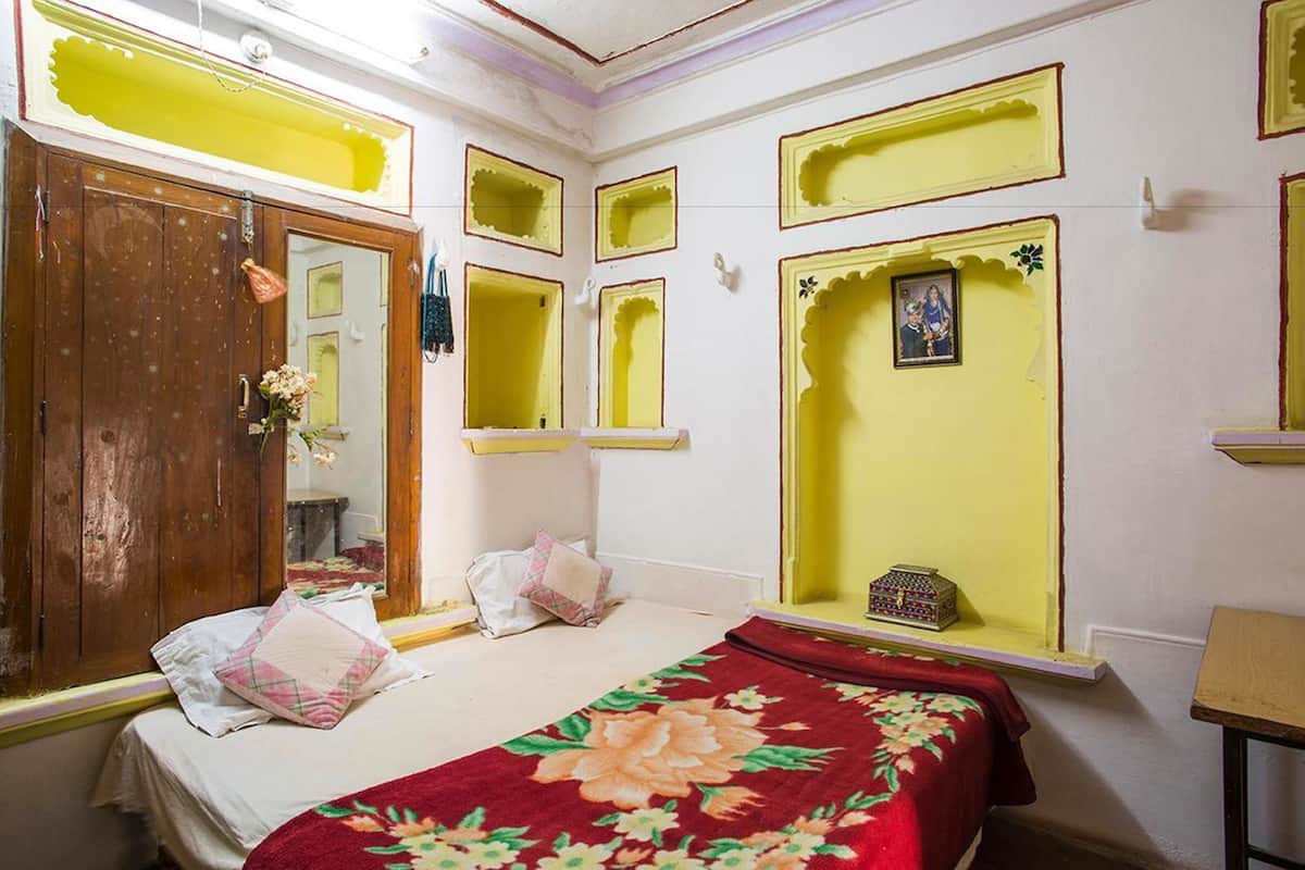 Un dormitorio con un armario de madera, una cama con colcha estampada y detalles decorativos amarillos en las paredes.