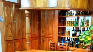 Un comptoir de bar en bois doté d’un plan de travail incurvé, de plusieurs étagères remplies de bouteilles et d’une plante en pot.