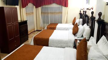 Habitación de hotel con dos camas, un armario, televisor, cortinas y una araña.