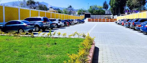 Um estacionamento com fileiras de carros e vista clara para montanhas ao fundo.