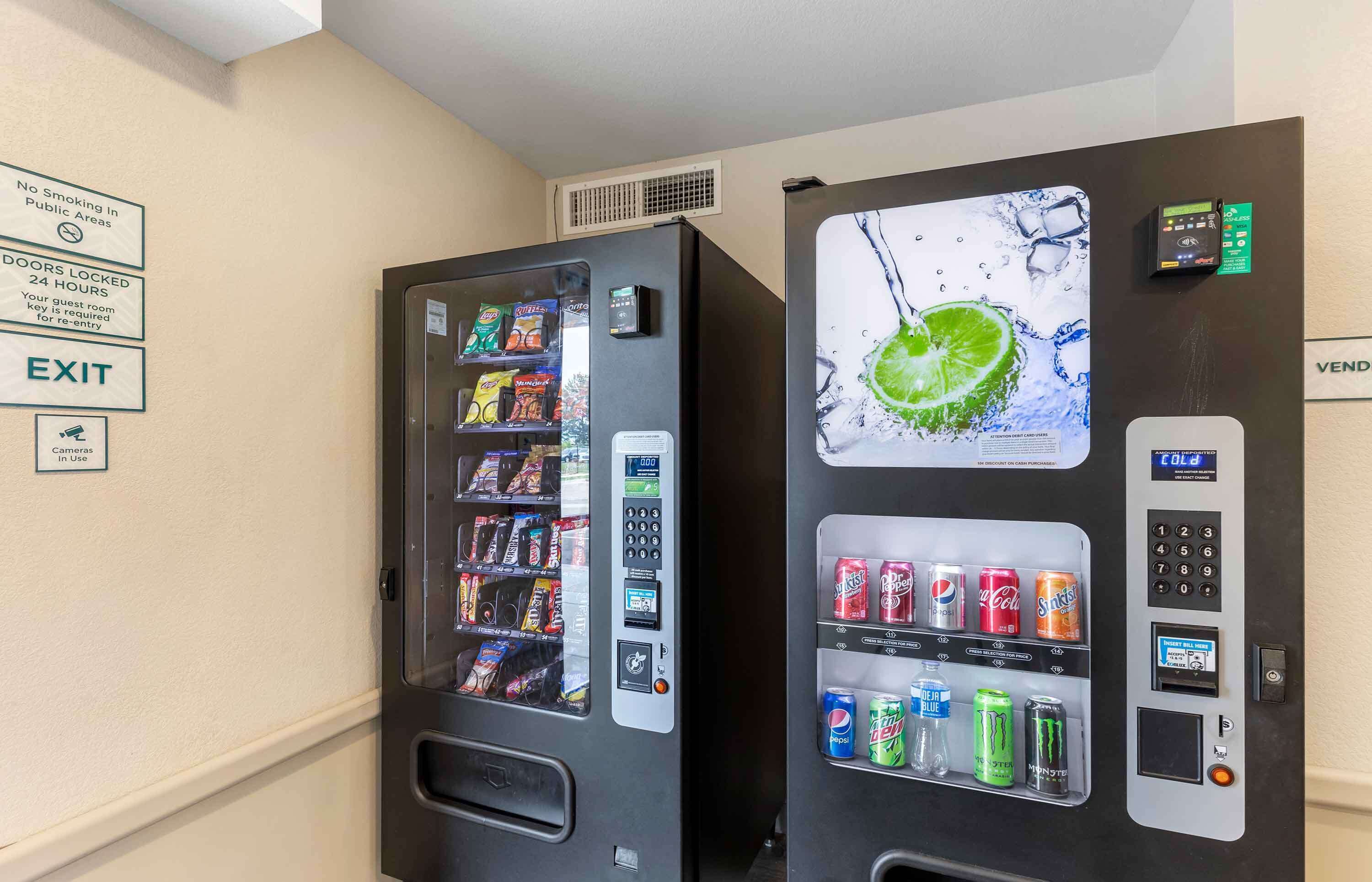 Two vending machines with snacks and drinks, a sign indicating no smoking, and an exit sign.