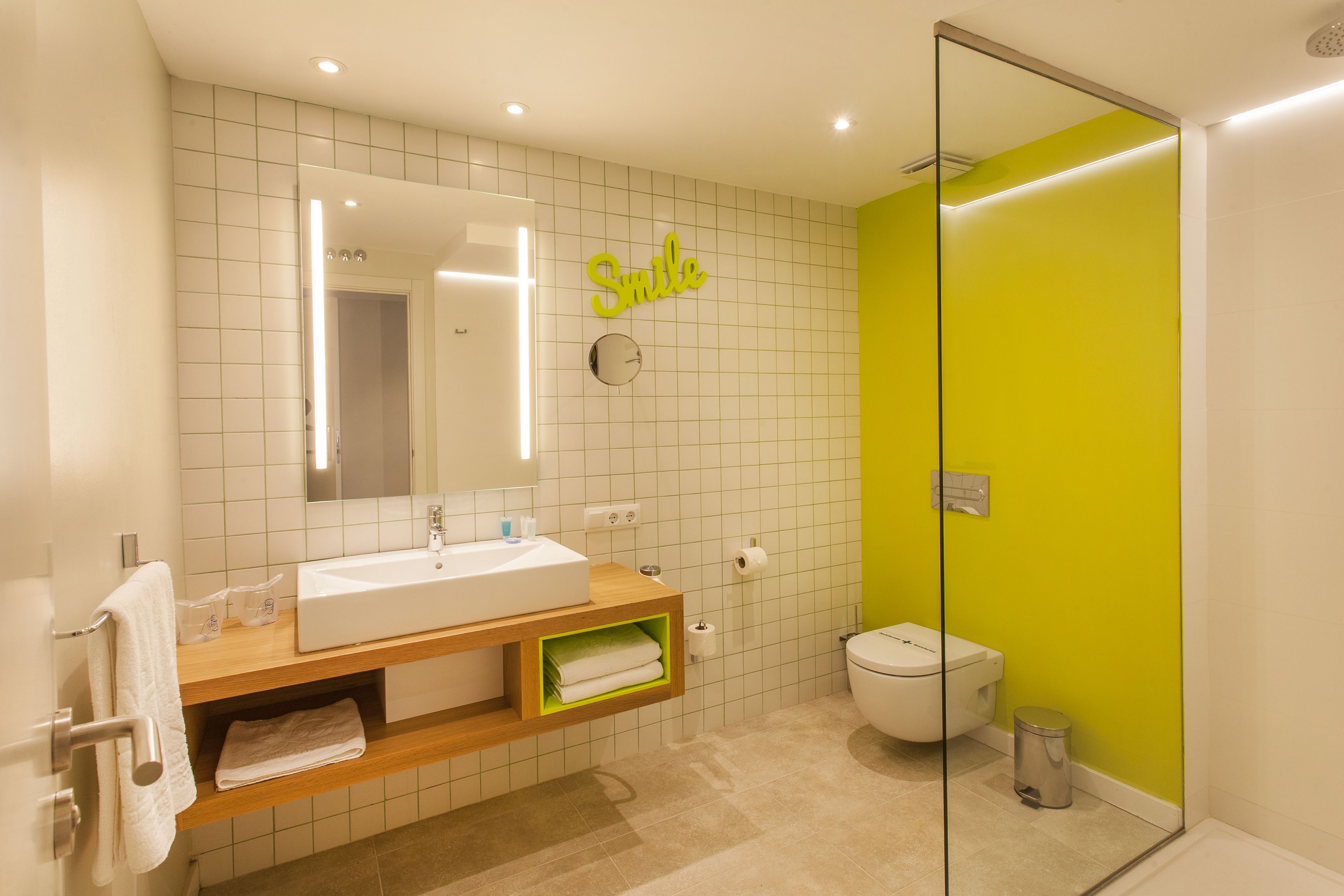 A modern bathroom with a white sink, mirror, and green accent wall.