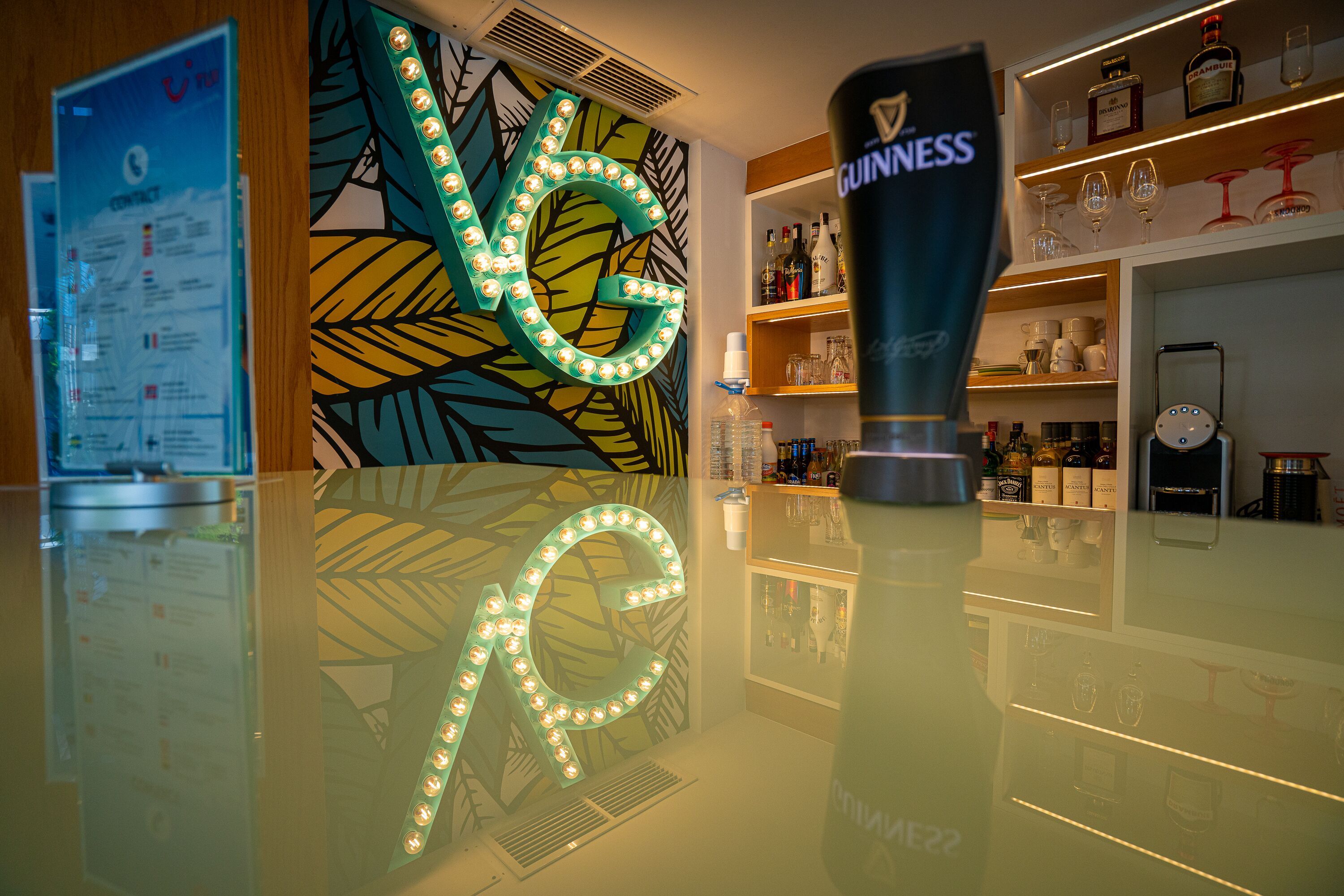 A bar area with a Guinness bottle, a menu board, and a decorative wall with illuminated letters.