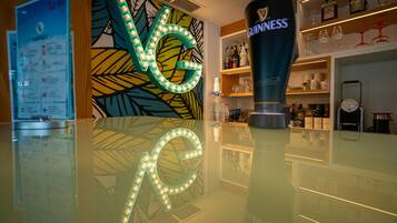 A bar area with a Guinness bottle, a menu board, and a decorative wall with illuminated letters.