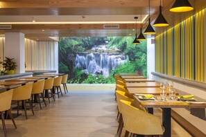 A restaurant with a waterfall mural, wooden tables, yellow chairs, and pendant lighting. - Vanilla Garden Boutique Hotel - Adults Only (Arona)