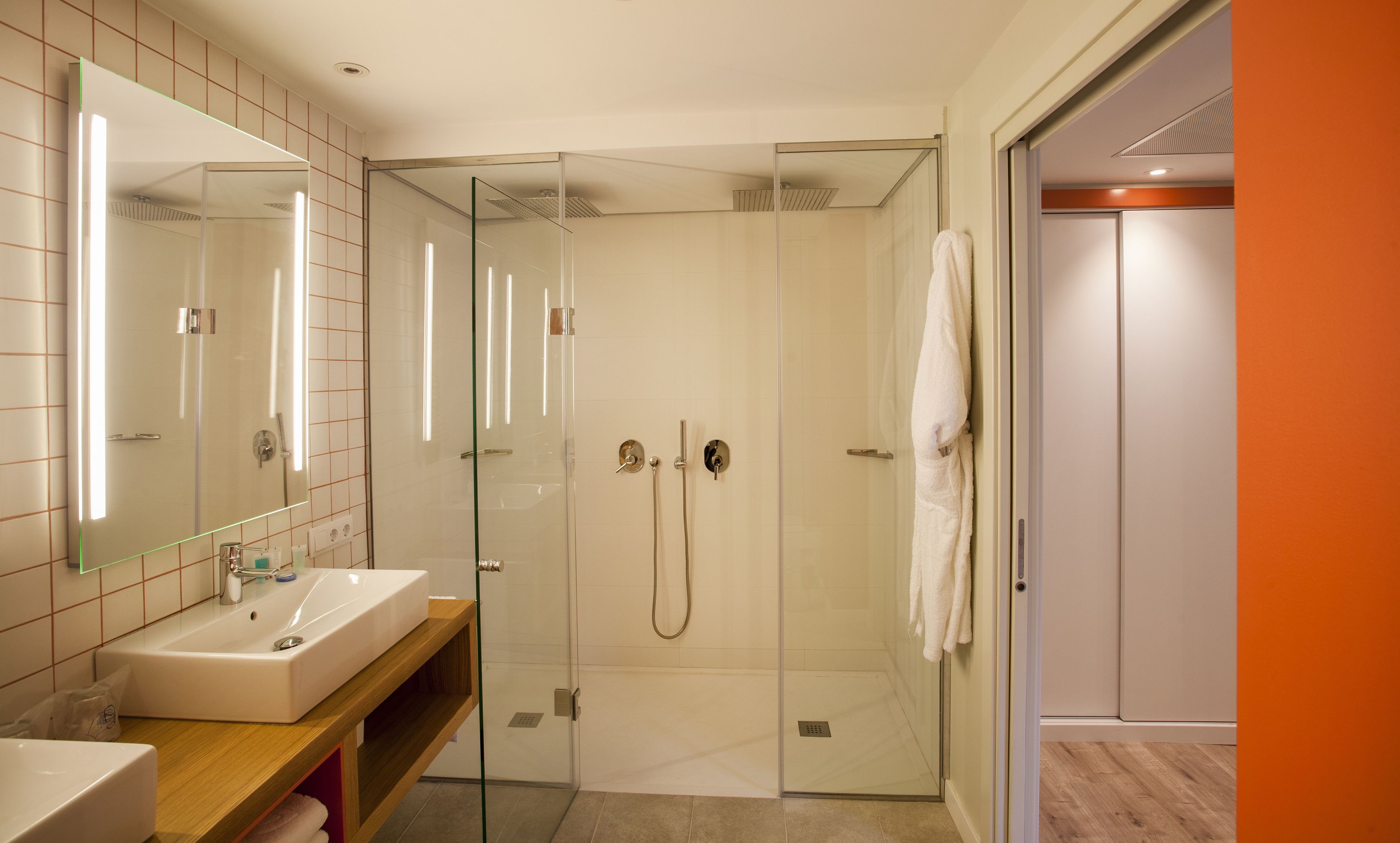 Un baño moderno con ducha envuelta en cristal, un lavabo y un espejo.
