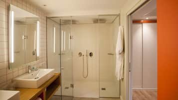 Un baño moderno con ducha envuelta en cristal, un lavabo y un espejo.