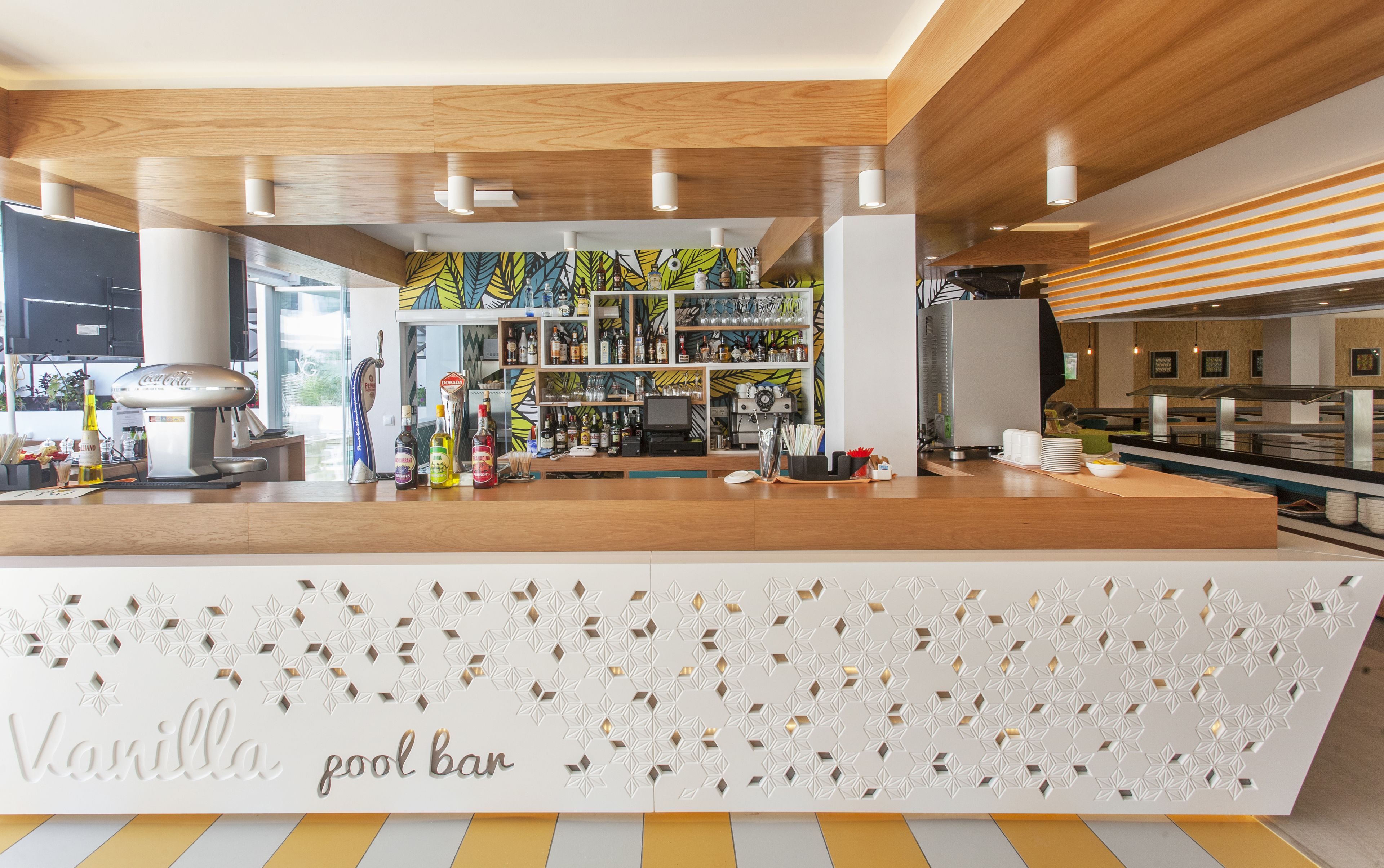 Een poolbar met een witte toonbank, planken met flessen en een Coca-Cola automaat.