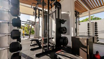 A gym with various exercise equipment, including dumbbells, a bench, and weight machines.
