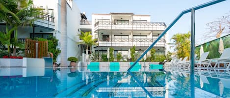 Una piscina al aire libre, sombrillas, sillones reclinables de piscina