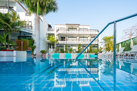 Una piscina al aire libre, sombrillas, sillones reclinables de piscina