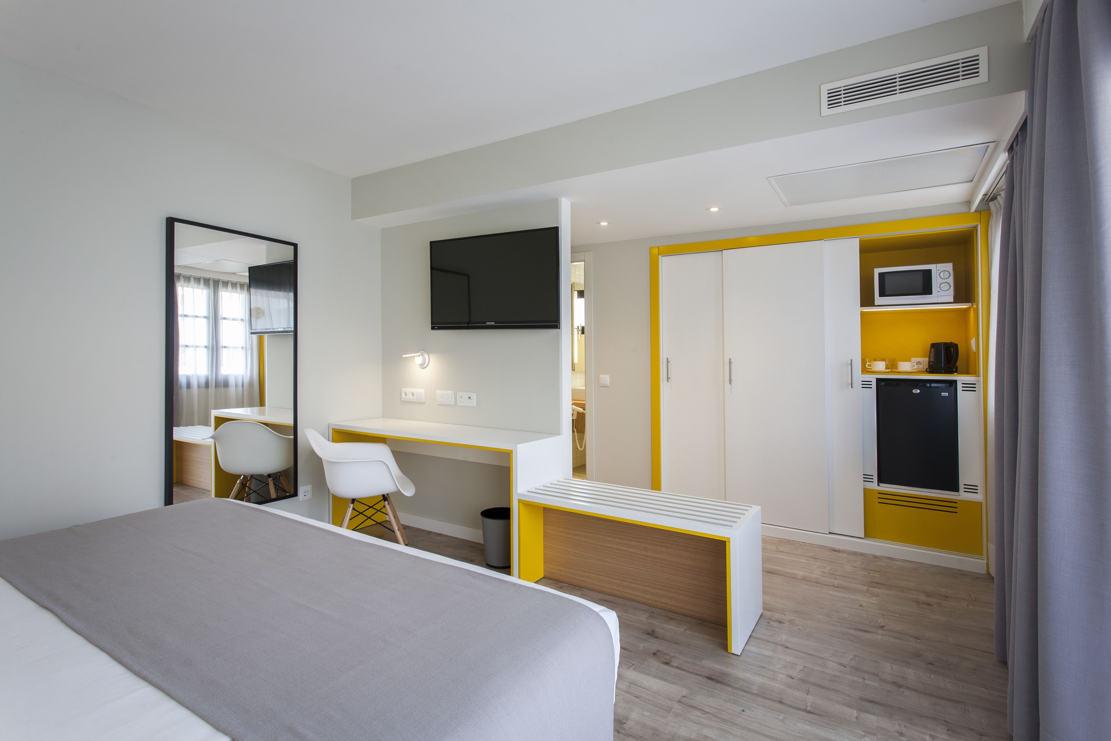 Une chambre d’hôtel équipée d’un lit, d’un bureau, d’une chaise, d’une télévision, d’un four à micro-ondes et d’une armoire.