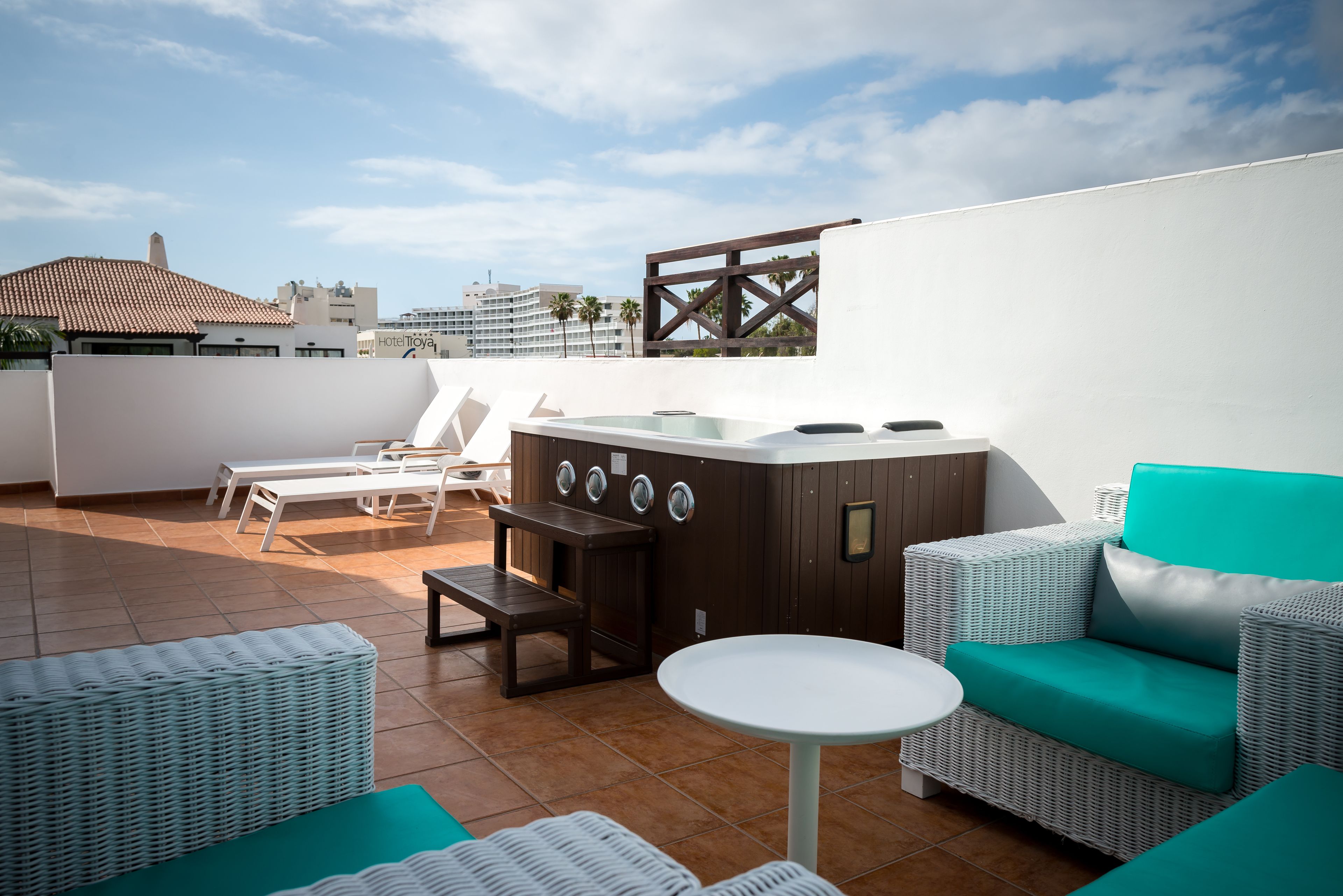 Una terrazza sul tetto con idromassaggio, mobili in vimini e vista sullo skyline della città.