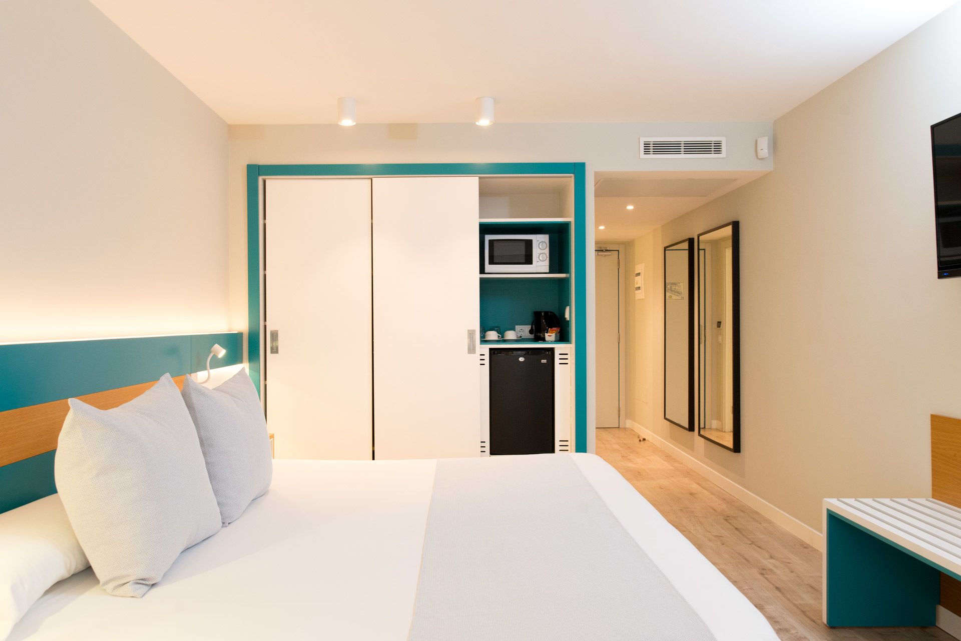 Una habitación de hotel con una cama, un escritorio, un microondas y un refrigerador pequeño.