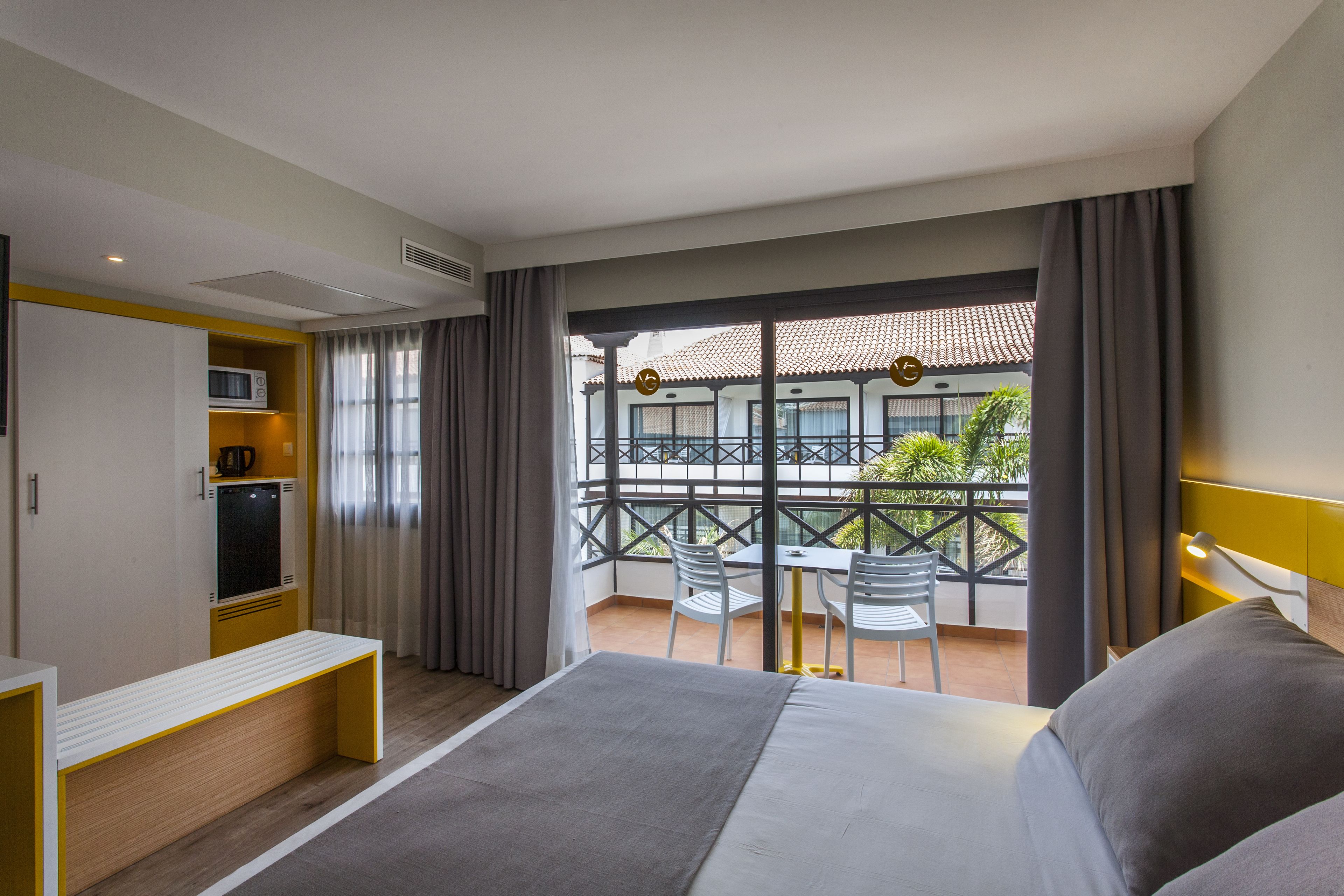 A hotel room with a balcony, a bed, a desk, and a chair.