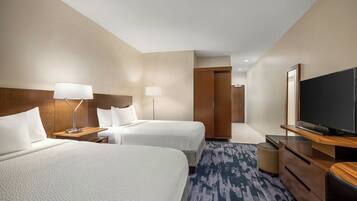 A hotel room with two beds, a flat-screen TV, a desk, and a lamp.