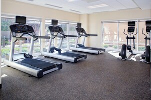 Un gimnasio con cintas de correr, bicicletas estáticas y máquinas de pesas.