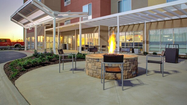 An outdoor patio with a stone fire pit and seating. - TownePlace Suites by Marriott Albany (Albany)