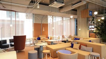 A modern lounge area with sofas, tables, and chairs arranged for socializing.