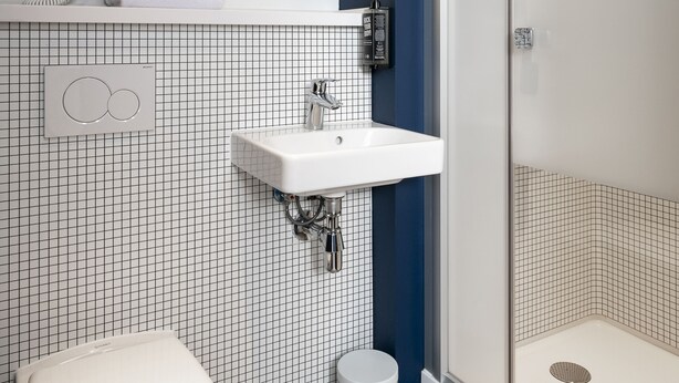 Ein modernes Badezimmer mit Toilette, Waschbecken, Spiegel und Dusche.