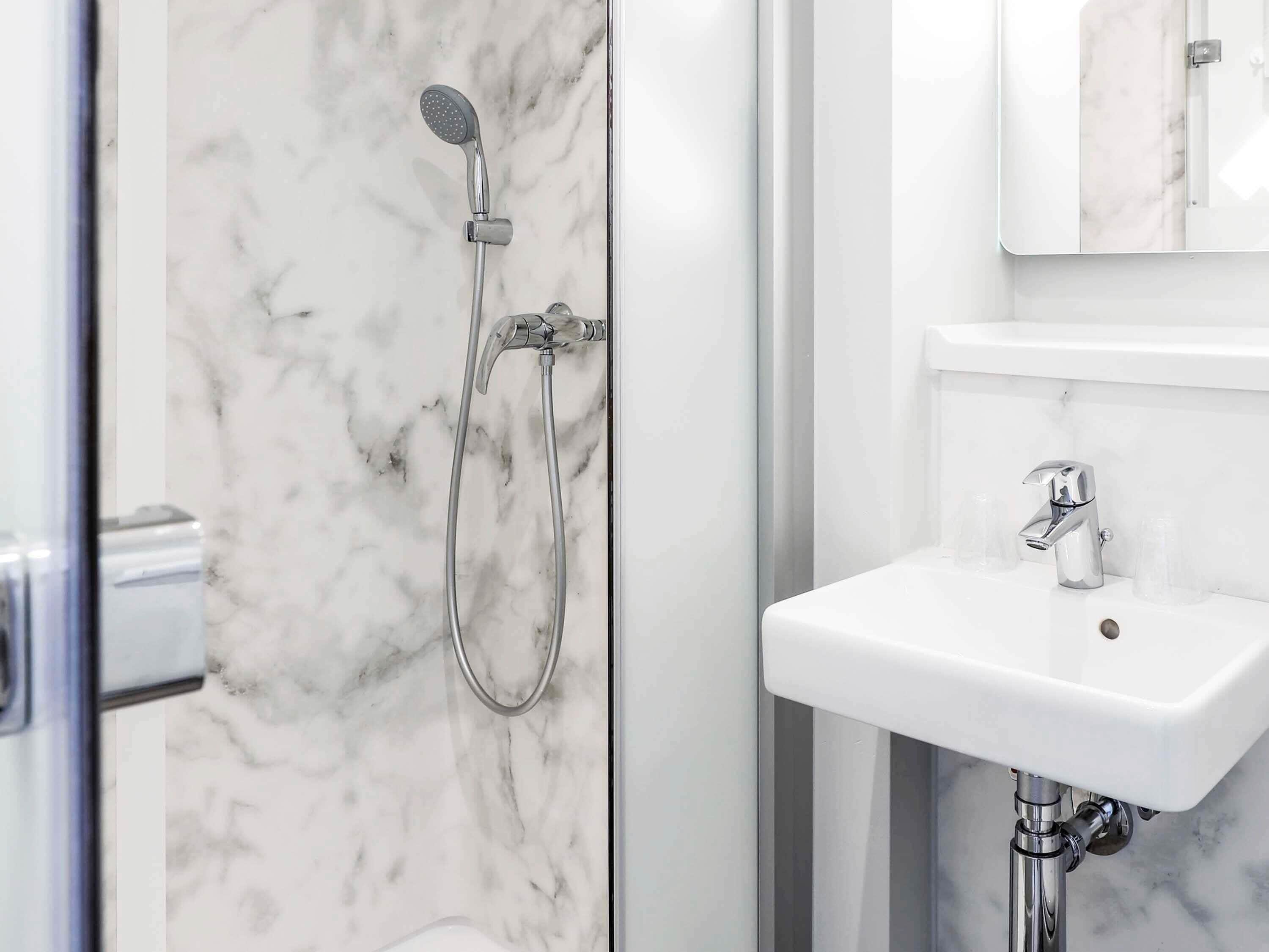 Un baño con ducha, lavabo y espejo.