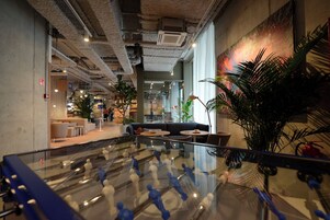 A modern indoor space with a glass table, seating areas, and indoor plants.