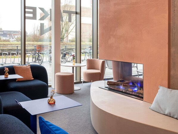 Un área de descanso moderna con sofá, sillones, una mesita y chimenea.