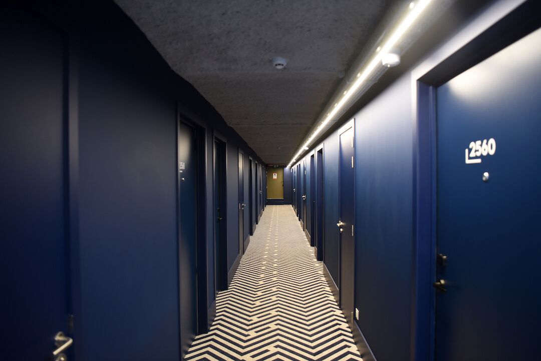 A long, narrow hallway with blue doors, each marked with a number.