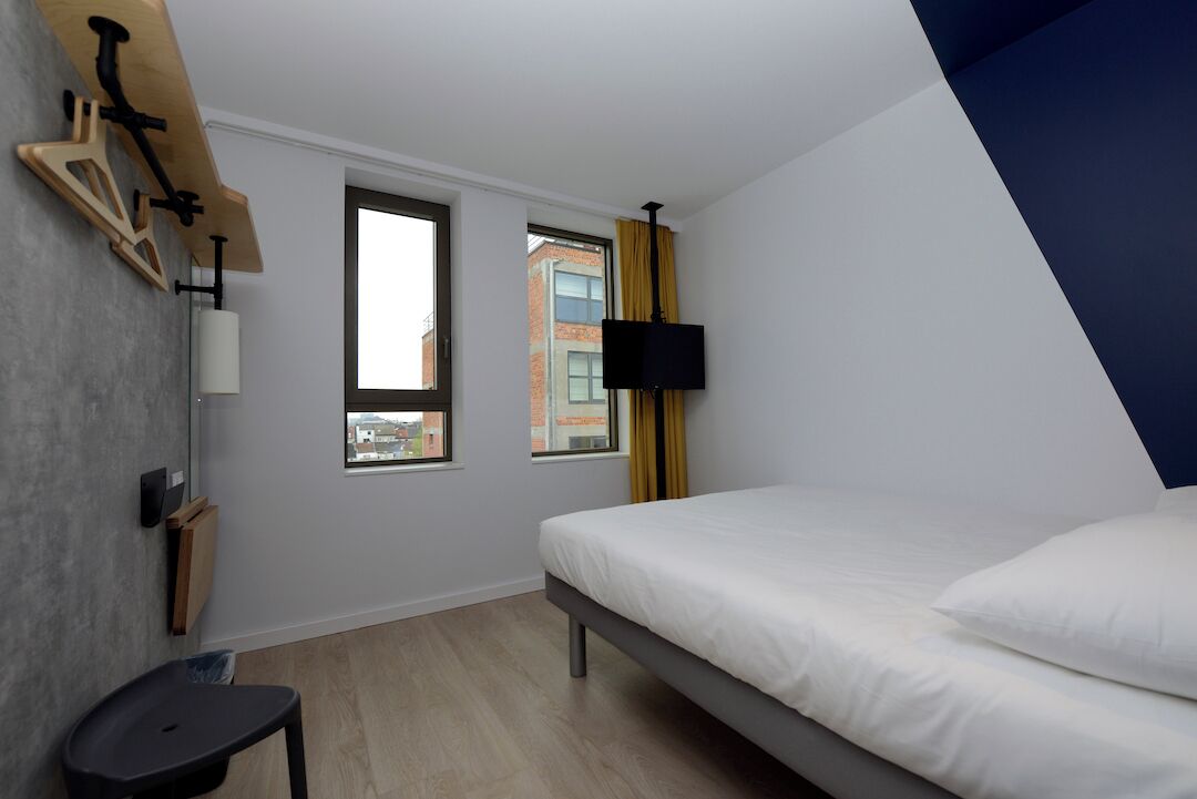 Una camera da letto con un letto, due finestre, una TV e un tavolino.