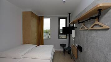 A modern hotel room with a bed, wardrobe, TV, and a wall-mounted drying rack.